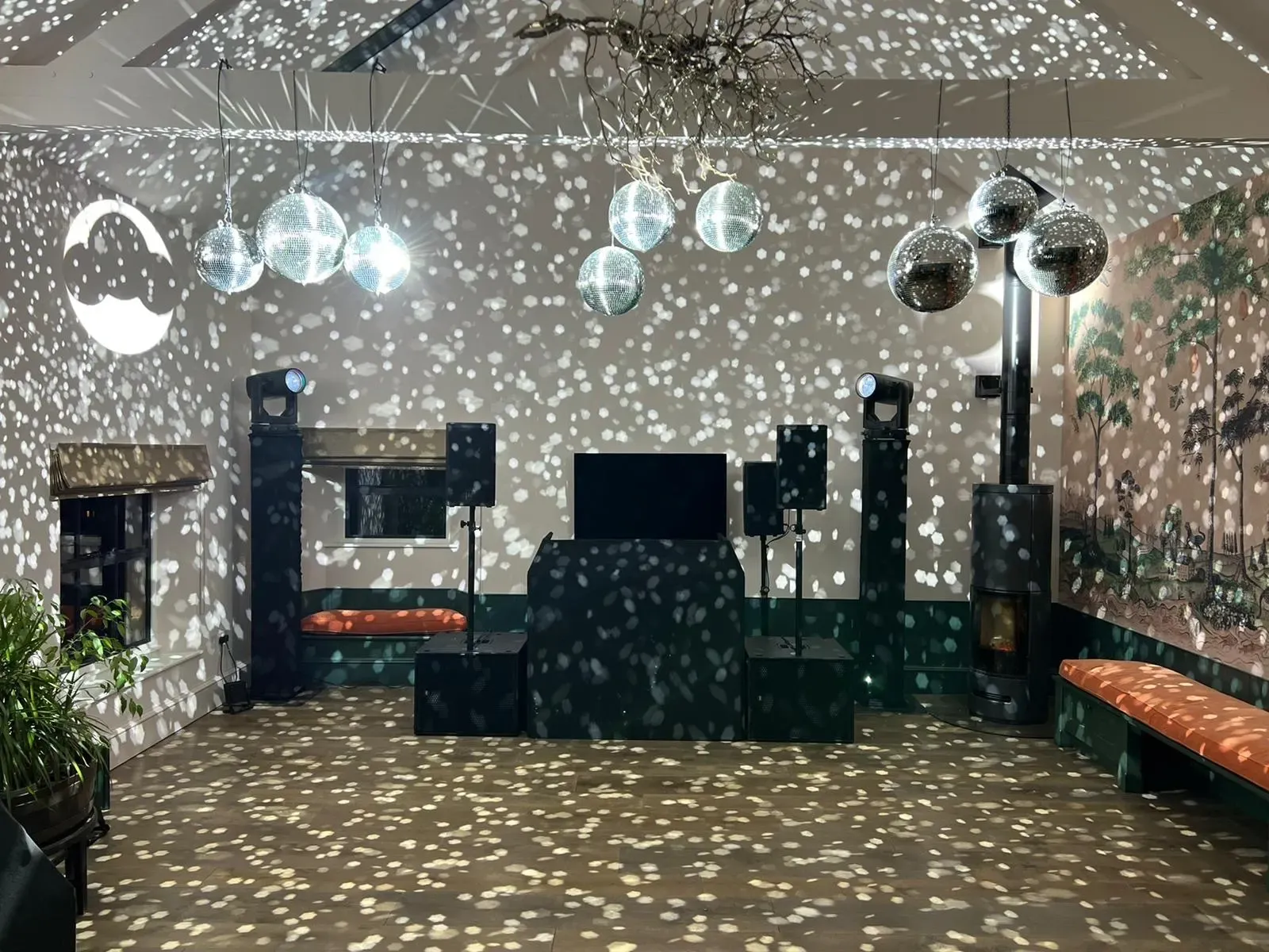 A mirror-ball cluster and pin spots covering the walls, floor and ceiling of a small room with a DJ booth and speakers